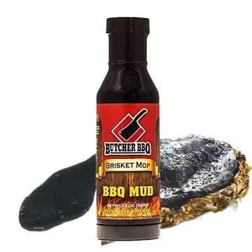 Bottle of Butcher BBQ Brisket Mop BBQ Mud with a wooden block and metal brush on a white background