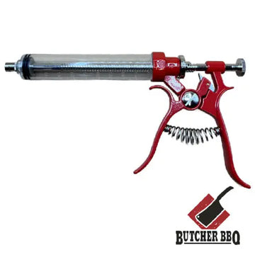 Red and silver syringe-like tool with a spring mechanism on a white background, featuring the Butcher BBQ logo.