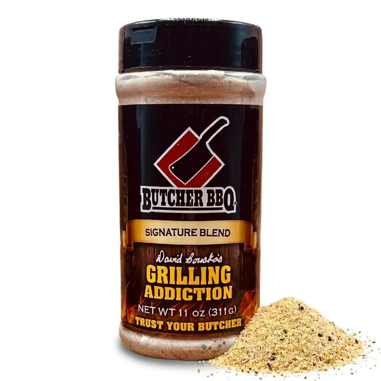 A bottle of Butcher BBQ Grilling Addiction seasoning with a small pile of the seasoning blend spilled in front, set against a plain white background.