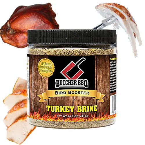 A jar of Butcher BBQ Bird Booster Turkey Brine shown on a white background with a whole roasted turkey and sliced cooked turkey pieces used as contextual food props. The product is a clear plastic jar with a black lid and a wood-grain label featuring the brand name 'Butcher BBQ' and the text 'Bird Booster' and 'Turkey Brine'.