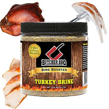A jar of Butcher BBQ Bird Booster Turkey Brine shown on a white background with a whole roasted turkey and sliced cooked turkey pieces used as contextual food props. The product is a clear plastic jar with a black lid and a wood-grain label featuring the brand name 'Butcher BBQ' and the text 'Bird Booster' and 'Turkey Brine'.