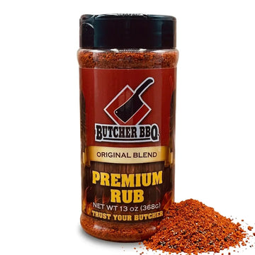 A 13 oz shaker bottle of Butcher BBQ Premium Rub Original Blend, shown with a small pile of the reddish-brown spice rub spilled in front on a white background.