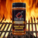 Butcher BBQ Savory Pecan Seasoning bottle on a grill with flames in the background