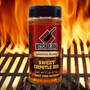 Bottle of Butcher BBQ Sweet Chipotle Rub on a grill with flames in the background